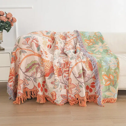 A cozy double cotton bohemian throw blanket with vibrant orange green floral pattern and soft fringed edges on cream