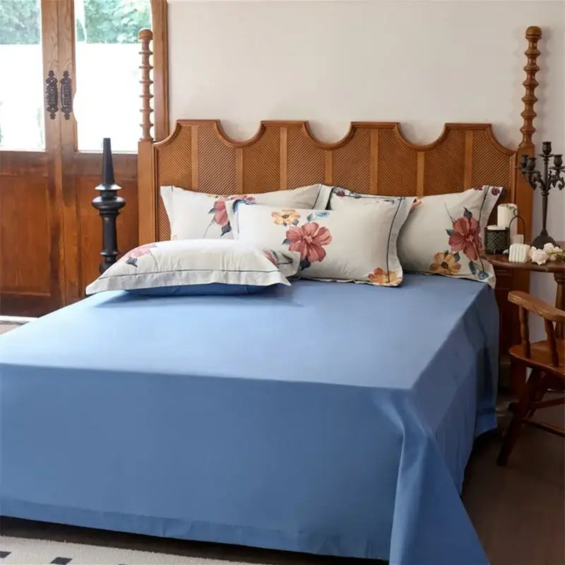 Blue satin egyptian cotton bedding sets with floral cream pillows on wooden bed frame for bedroom use