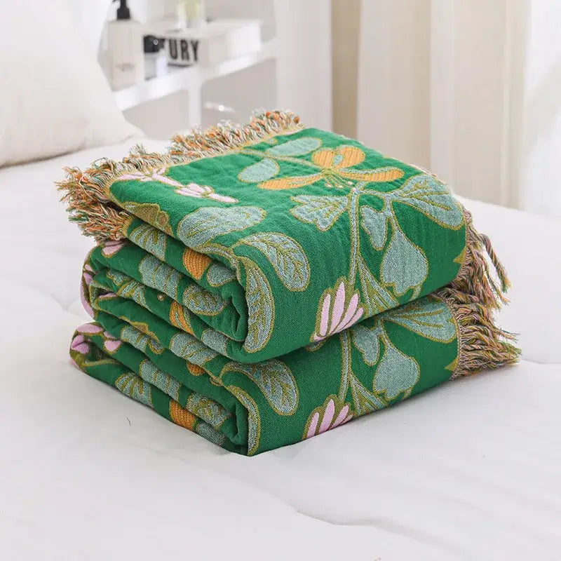 Stacked green sofa cover with embroidered floral patterns in light blue yellow and pink made of decorbites jacquard cotton gauze