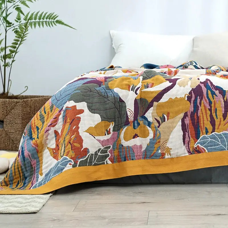 A vibrant floral embroidered cozy gauze cotton throw with abstract botanical pattern and mustard-yellow border
