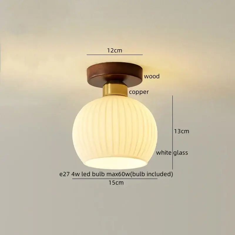 A warm-toned spherical white glass led ceiling lamp with vertical ridges, brass stem, and walnut base for living room