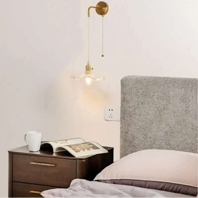 A brass-finished floral glass copper led wall sconce with a curved arm and glass-encased bulb for bathroom lighting