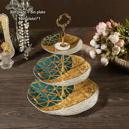 Three-tiered bone china fruit plates set with ornate gold and teal geometric floral design and silver trim tiered stand