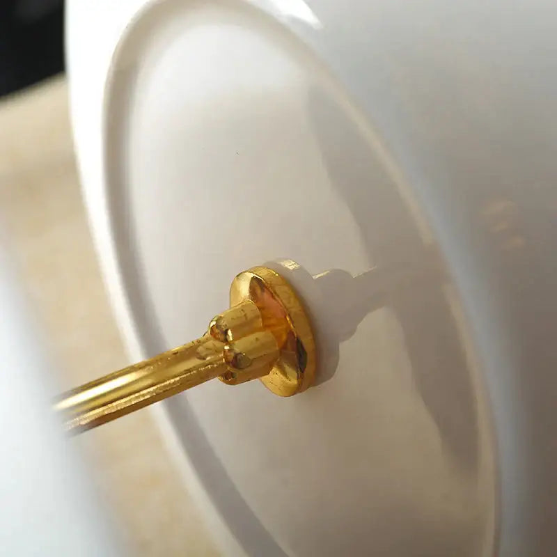 Gold-toned metal stem with circular base attached to underside of white bone china fruit plates set for tiered stand