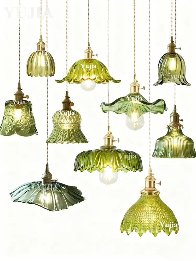 A collection of elegant pendant lights with green glass shades and brass fixtures featuring floral and ruffled designs