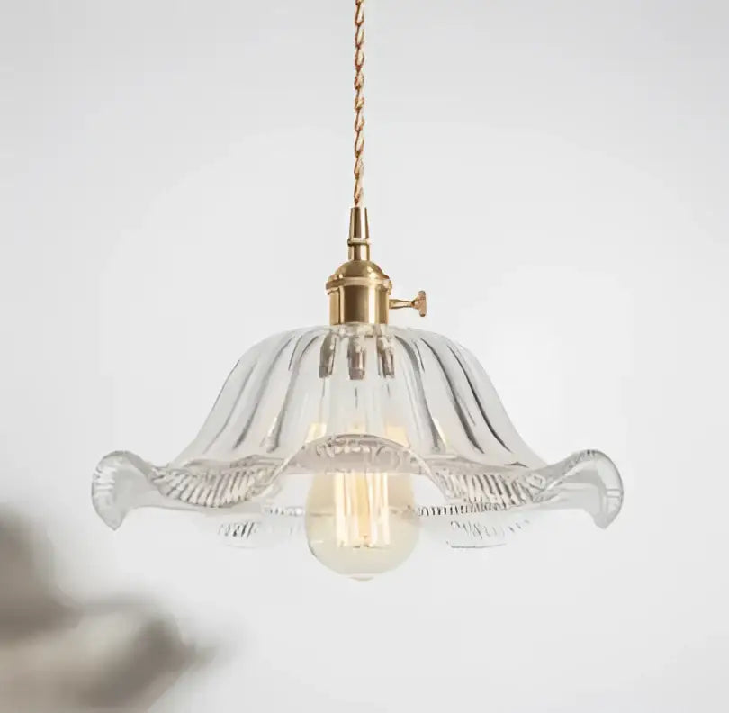 A delicate clear glass pendant light with fluted floral design and golden brass hardware for living room use