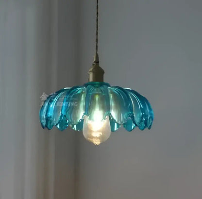 A delicate turquoise glass pendant light with petal design and golden brass hardware for living room use