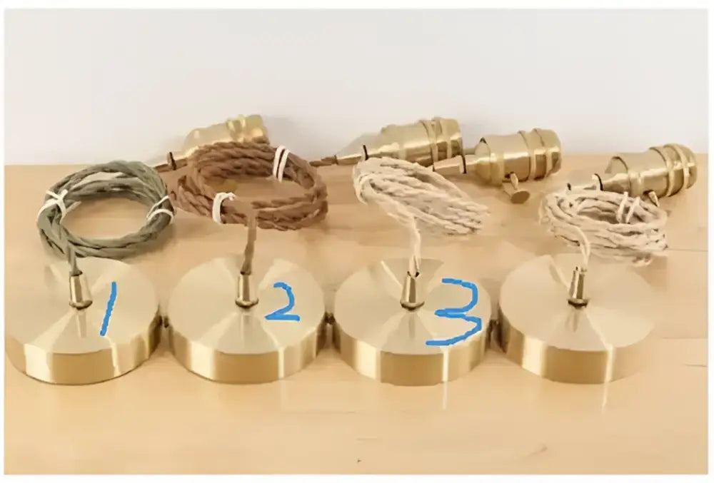 Four brass pendant lights with floral green glass pendant shades and colorful braided cords for living room use