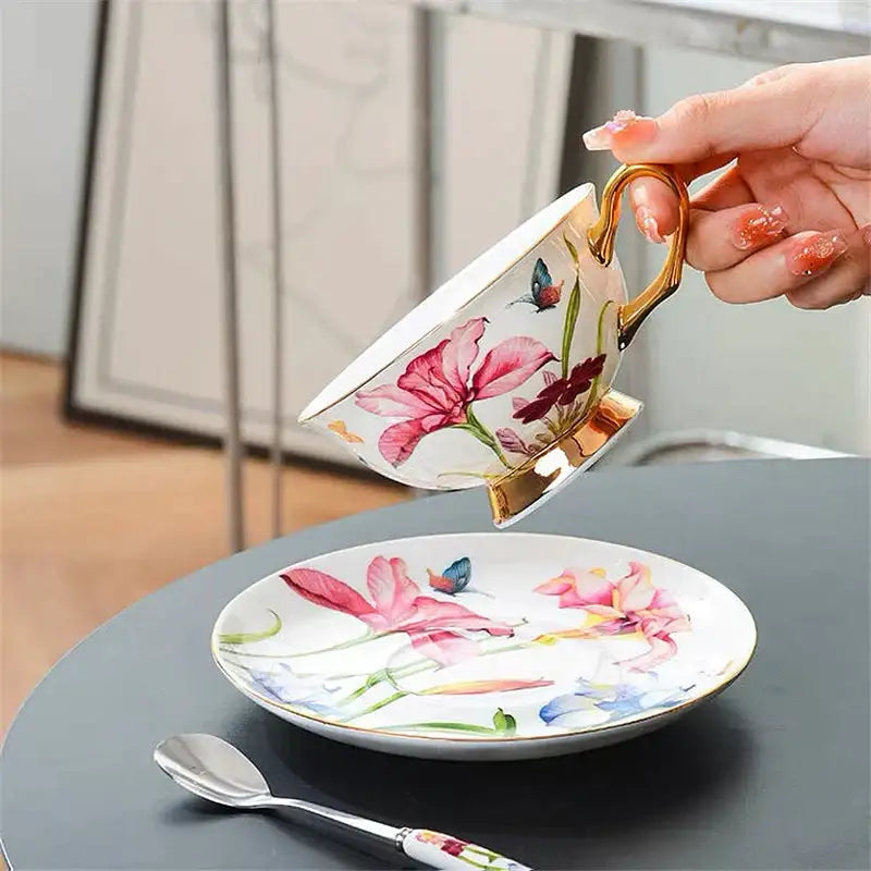 A delicate porcelain lily flower tea set cup with gold rim featuring pink flowers and blue butterflies on white background