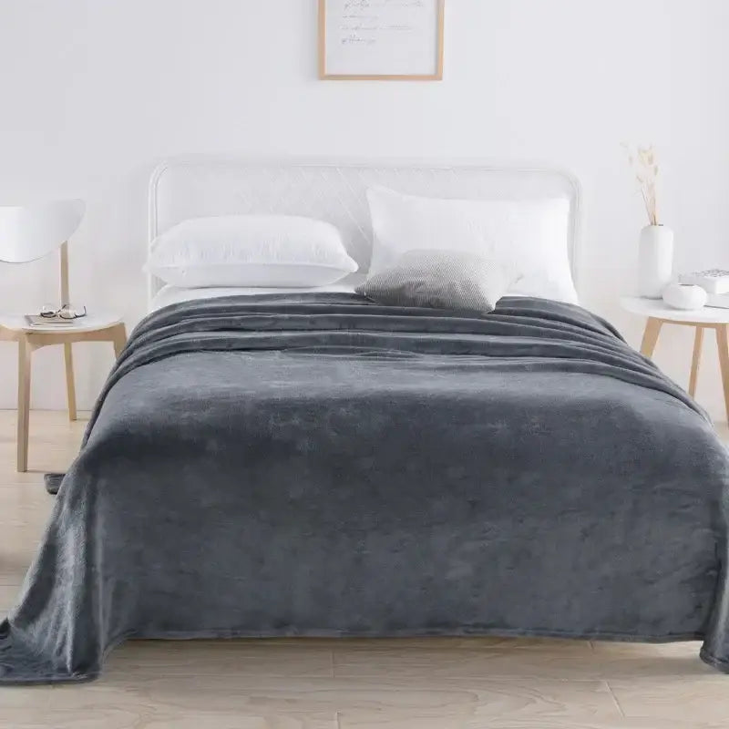 A plush dark gray decorbites coral fleece throw blanket with soft velvety texture draped over the bed for bedroom decor