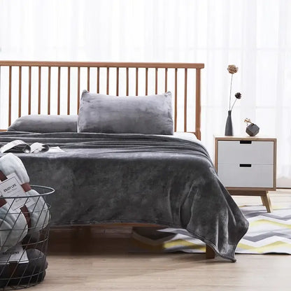 A plush dark gray coral fleece flannel throw blanket draped over a wooden bed frame for bedroom decorbites coral fleece