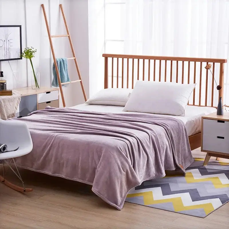 A soft lavender coral fleece flannel flower blanket draped over a wooden bed for decorbites coral fleece bedroom decor