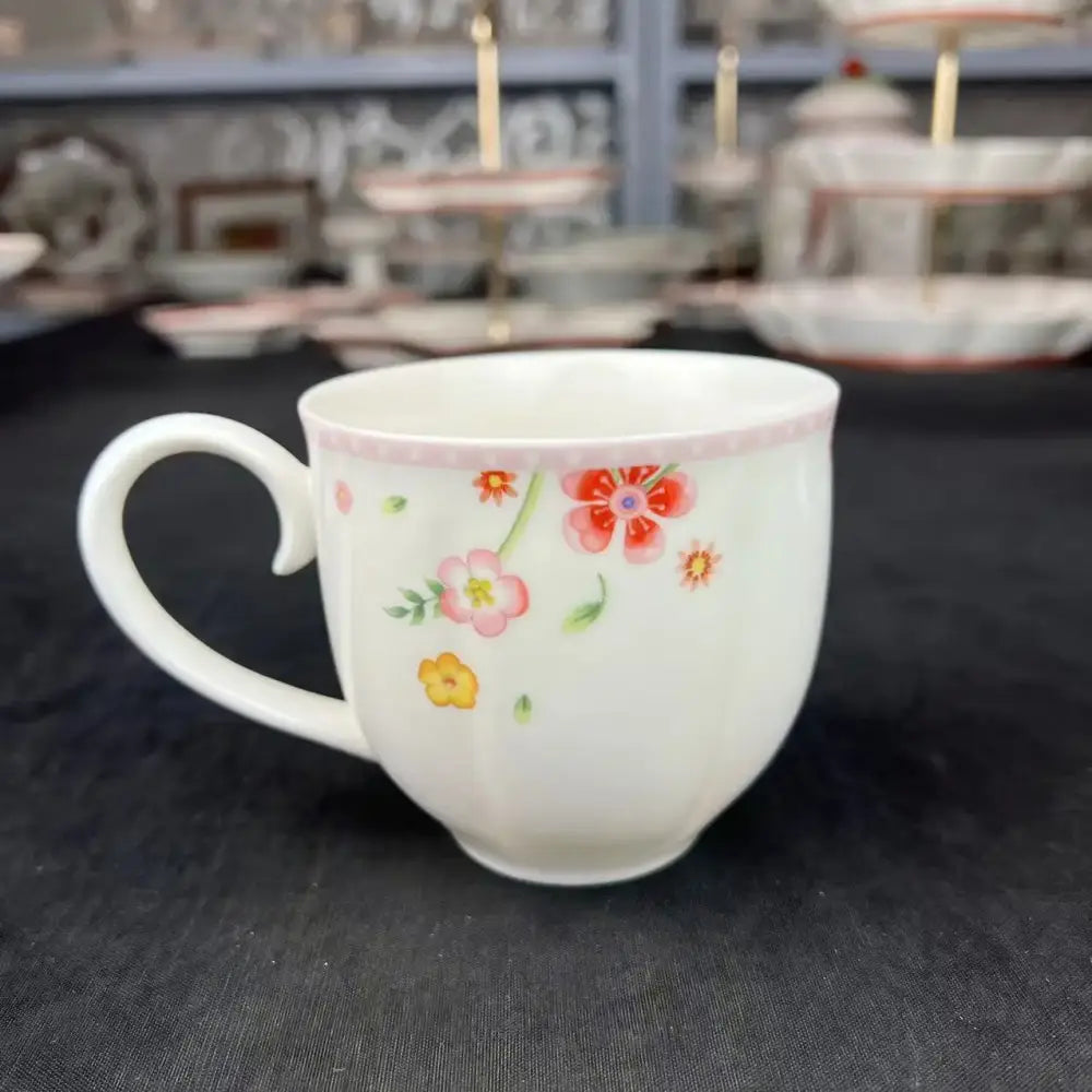 A white ceramic mug with pink and yellow floral patterns and a pink rim from a tulip dinnerware set