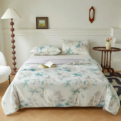 A soft quilted summer quilt with a delicate knitted cotton print in teal and gray tones on off-white background