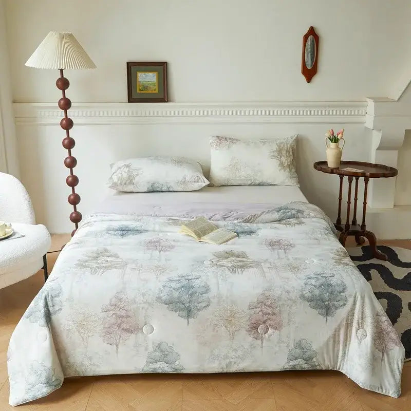 A cream summer quilt with a knitted cotton print of forest trees in muted blues and purples from decorbites