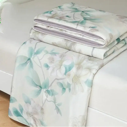 A folded floral teal and white decorbites knitted cotton print summer quilt with subtle gray accents