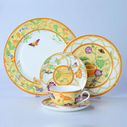 A vibrant yellow bone dinnerware set with floral and butterfly motifs in orange purple and green accents