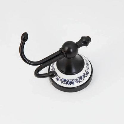 Black stainless steel double robe hook with white ceramic base and blue floral decorbites stainless steel bathroom hook
