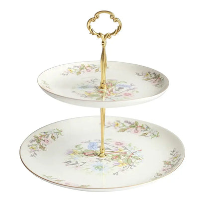 A delicate two-tiered floral white bone china tea set tray with ornate gold-toned handles enhances the tea-drinking experience