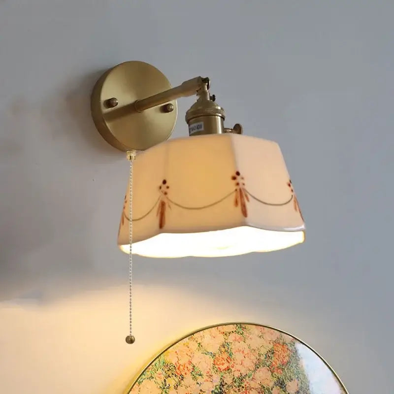 Vintage-style brass led wall light with cream ceramic shade featuring delicate brown floral and chain patterns for bedroom use