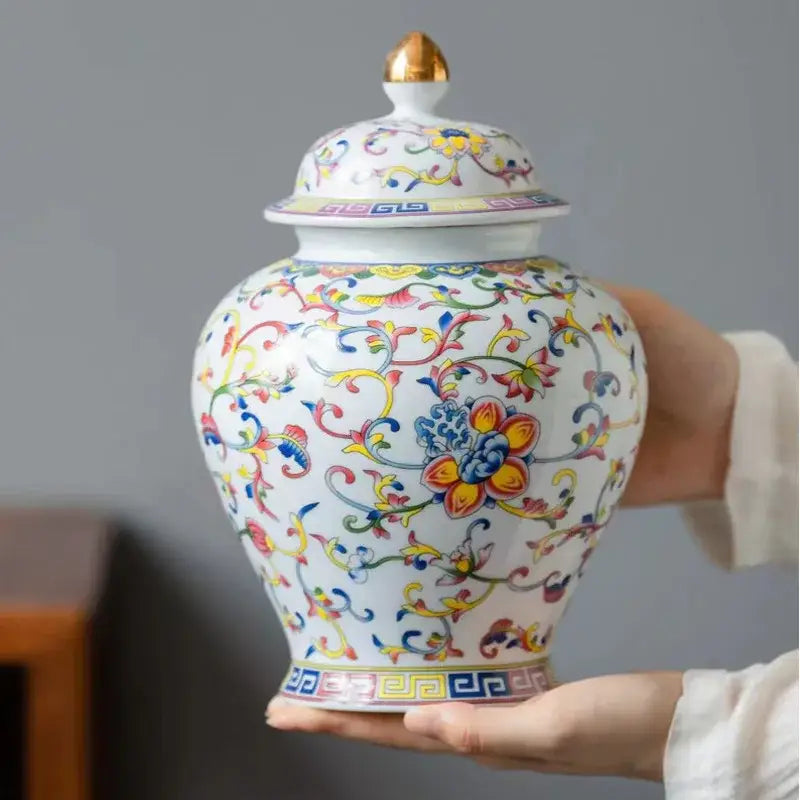 White enamelled porcelain tea caddy ginger jar with gold-tipped lid and vibrant multicolored floral vine patterns
