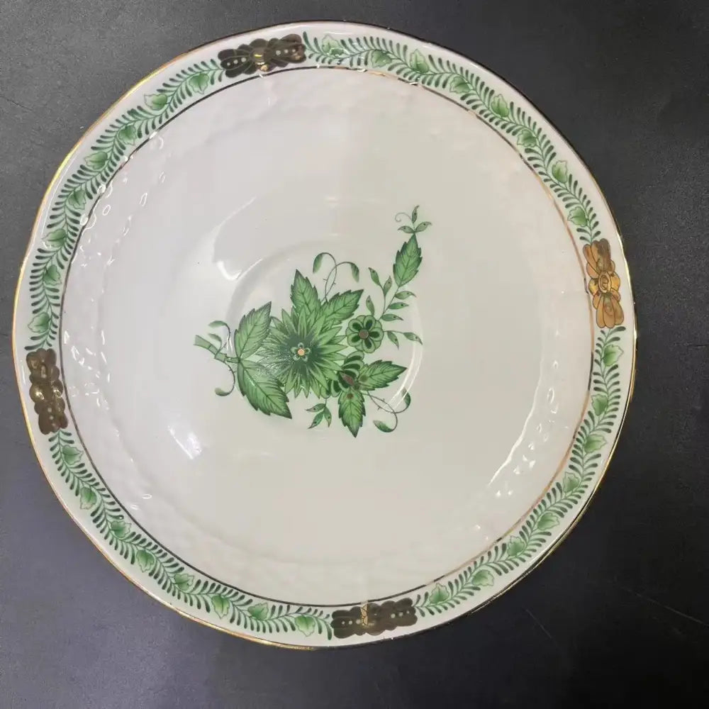 A white porcelain tea cup set with green floral design gold trim and ornate golden handles for dining room use