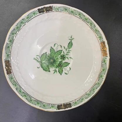 A white porcelain tea cup set with green floral design gold trim and ornate golden handles for dining room use
