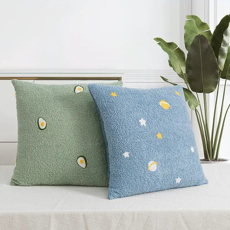 Two plush pillow covers in avocado green with embroidered slices and blue with planets for decorbites fluffy comfort pillow