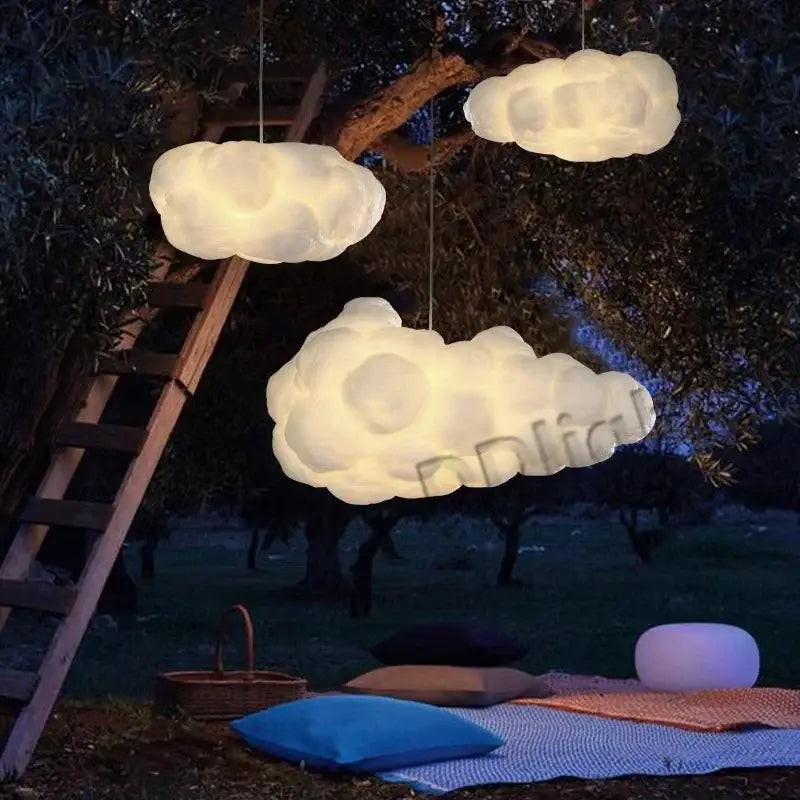 Three glowing fluffy white cloud ceiling chandelier pendant lights hanging outdoors against a dark backdrop