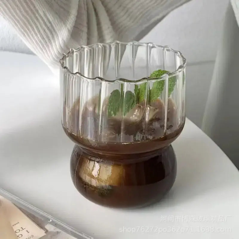 Clear glass coffee mug with fluted rim and ribbed sides filled with iced coffee and mint by decorbites glass coffee