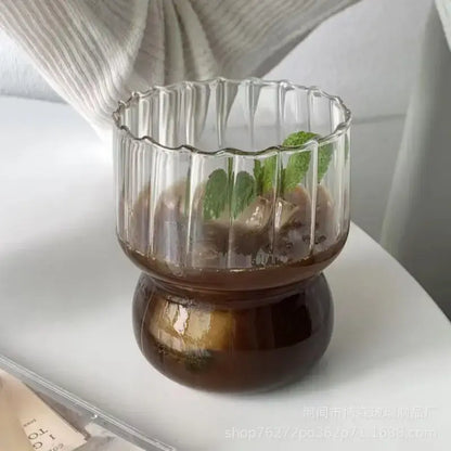 Clear glass coffee mug with fluted rim and ribbed sides filled with iced coffee and mint by decorbites glass coffee