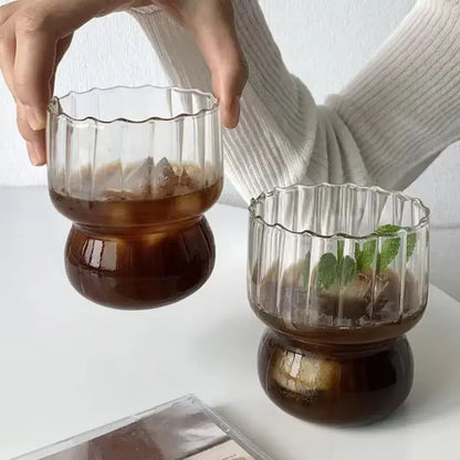 Clear glass coffee mug with fluted rim and bulbous base filled with iced coffee by decorbites glass coffee