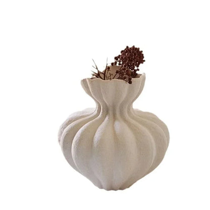 A white ceramic French vase with a fluted bulbous body and scalloped rim holding dried brown flowers for home decor