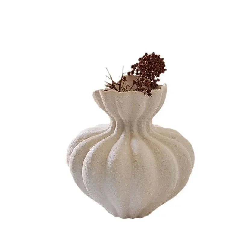 A white ceramic French vase with a fluted bulbous body and scalloped rim holding dried brown flowers for home decor