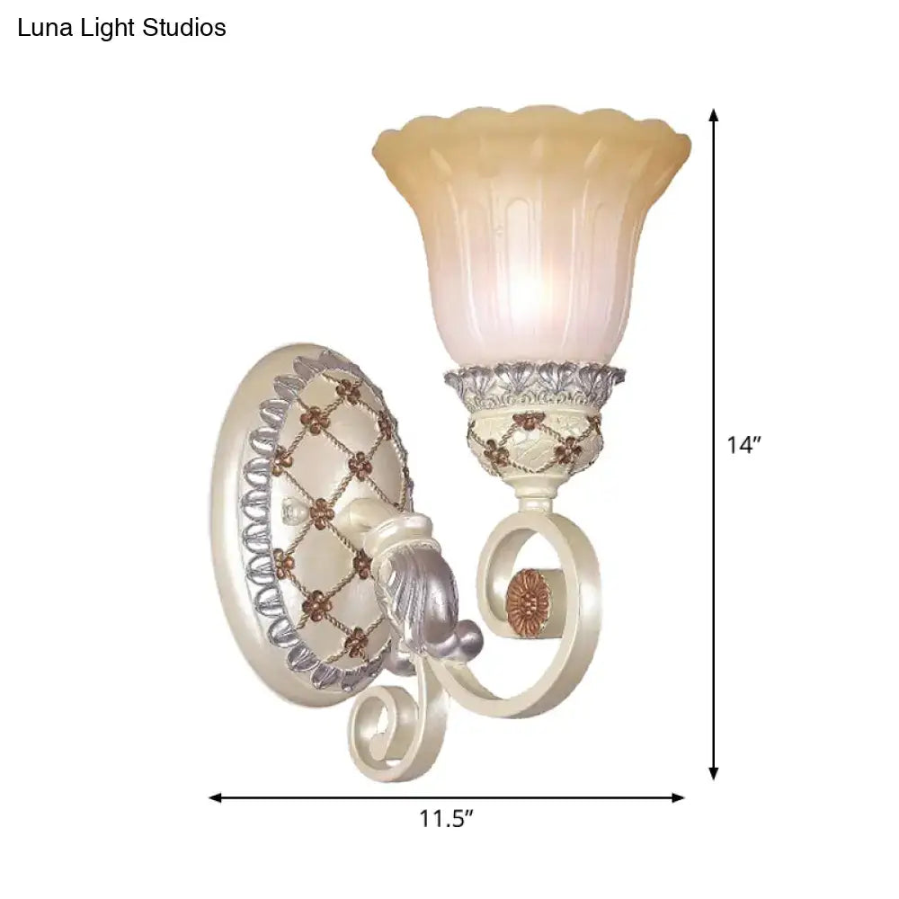 Cream-colored and silver-toned ornate wall sconce with fluted frosted opaline glass and gold light for living room use