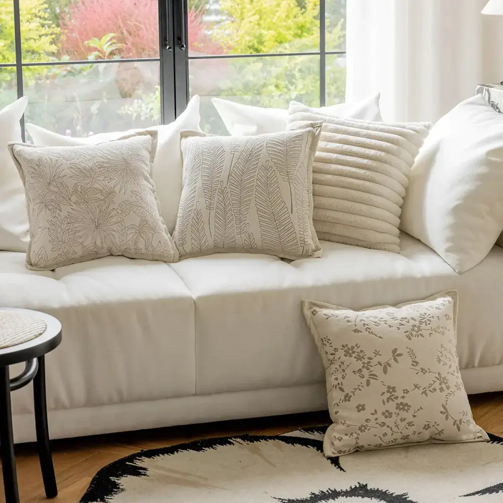 Beige french cream jacquard pillow covers with delicate embroidered leaf and floral patterns on white sofa decorbites