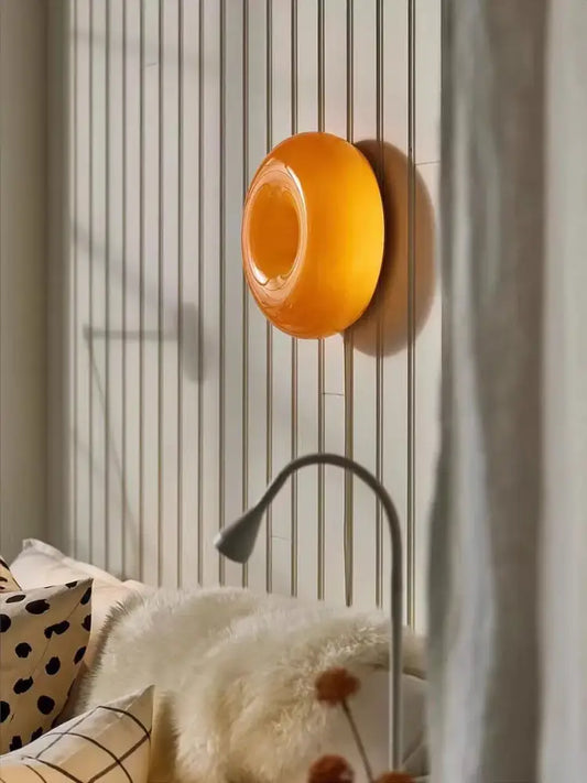A warm translucent orange glossy French decorative wall lamp with smooth finish ideal for bedside bedroom decor