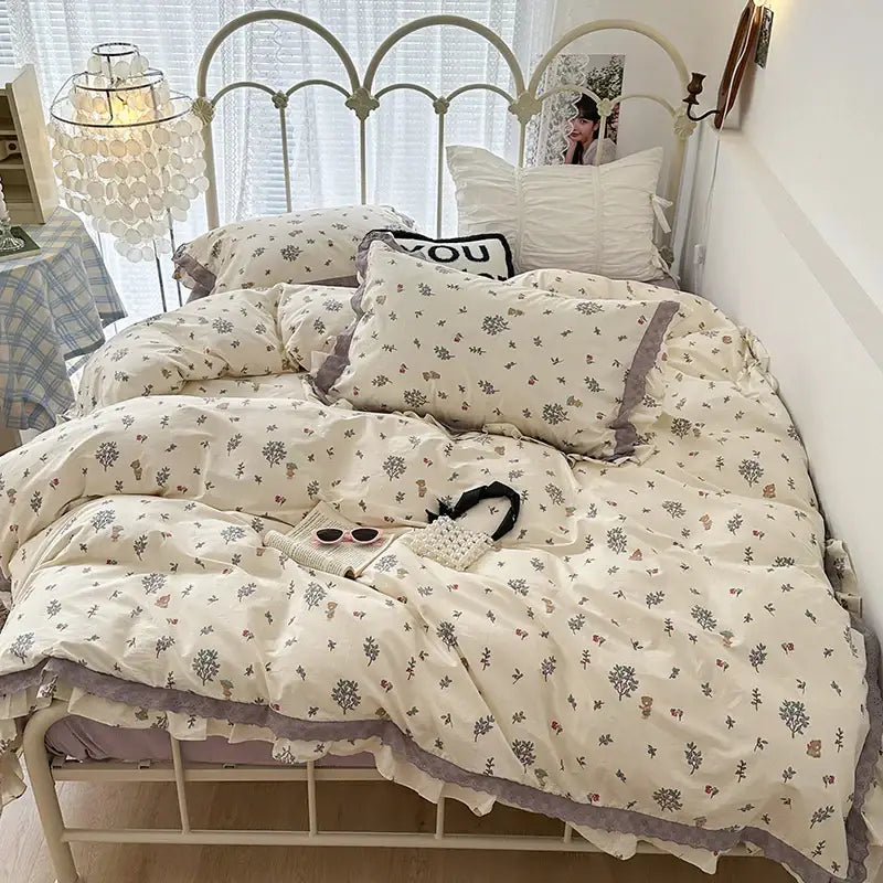 Cream-colored bedding set with double layer lace ruffles and gray pink botanical prints in muted lavender edges