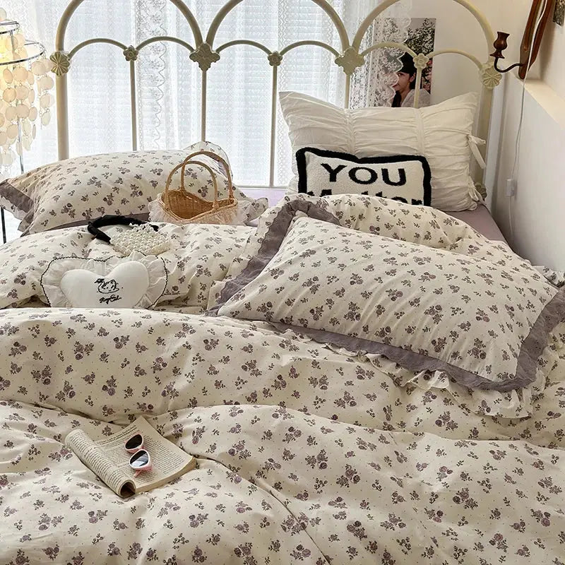 Cream-colored bedding set with double layer lace ruffles featuring delicate gray blossoms and ruffled edges
