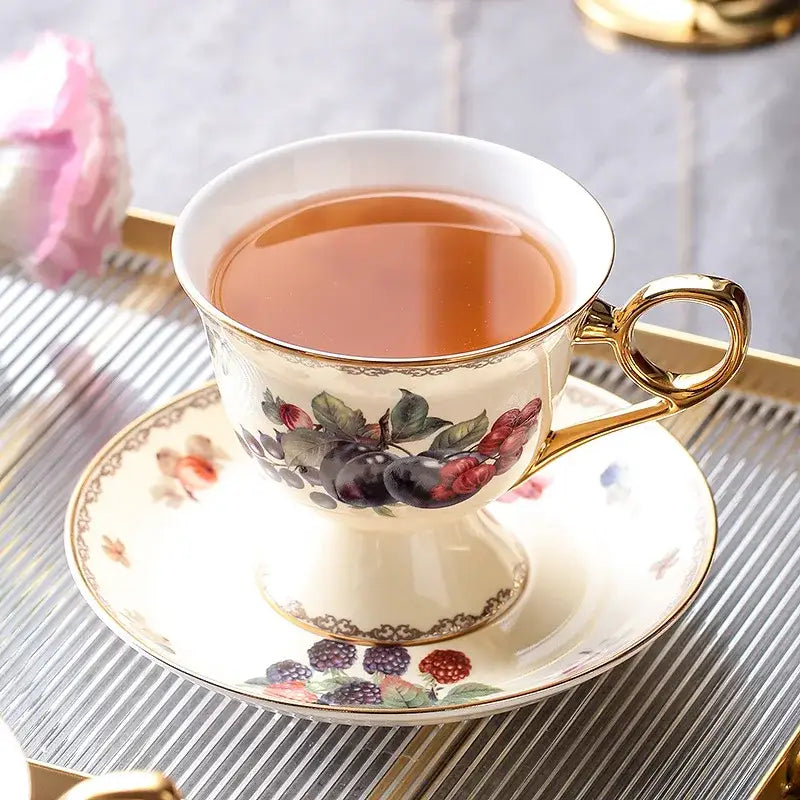 Elegant cream-colored porcelain decorbites bone china tea cup with gold trim and hand-painted berry motif on saucer