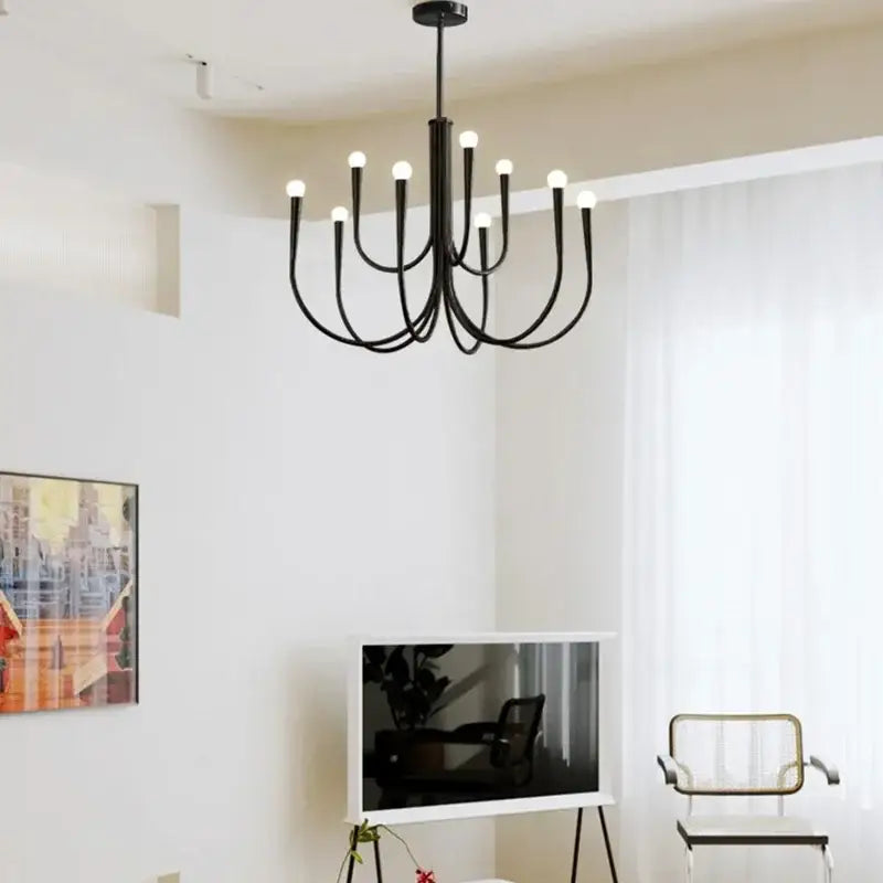 Black metal pendant light chandelier with curved arms and glowing bulbs for dining room in french style gold and black