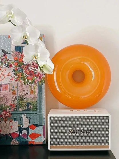 Vibrant orange glossy ceramic decorative wall lamp resting on white marshall speaker for bedroom use