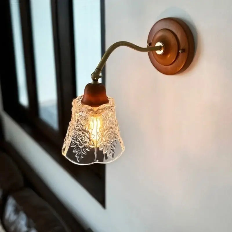 A warm-toned french vintage copper wall sconce with clear floral glass shade and wooden base for bedroom decorbites decor