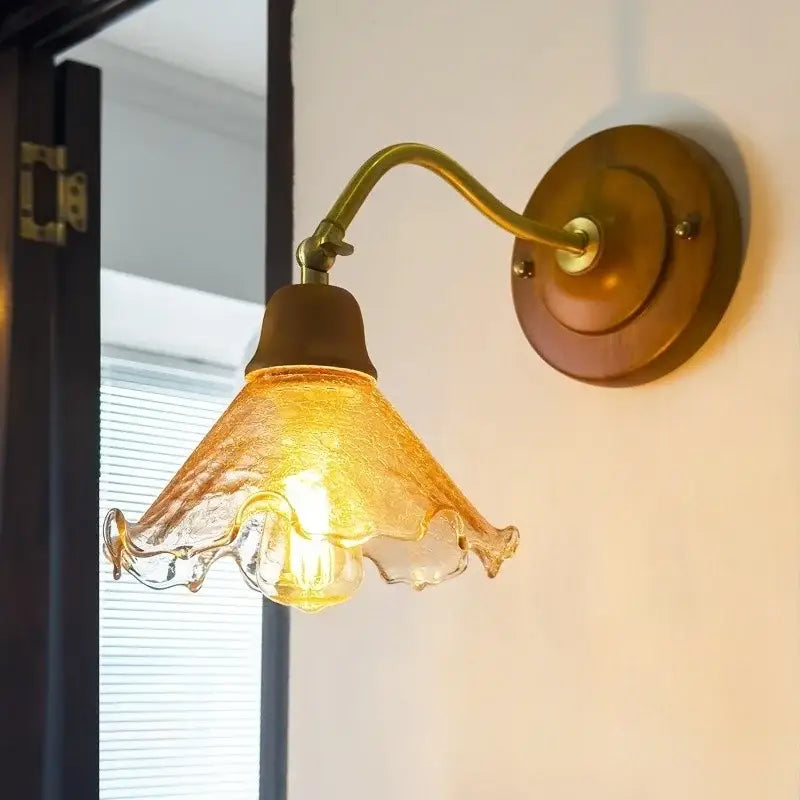 A warm amber glass wall sconce with ruffled hand-blown design and brass metal arm decorbites french vintage copper
