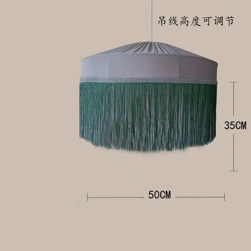A cylindrical pendant light with light gray fabric top and long green tassels in a French vintage tassel pendant light design