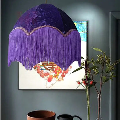 A deep purple velvet beauvamp tassel pendant light with cascading fringe and gold-trimmed edge for living room