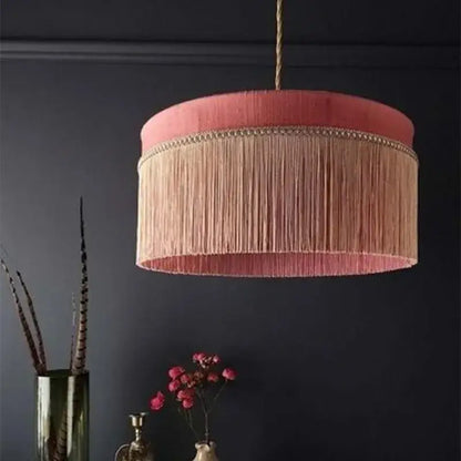 A pink velvet beauvamp tassel pendant light with peach tassels and ornate gold trim for living room decor