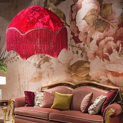 A plush vibrant red velvet pendant light with scalloped edge and cascading fringe in a french vintage style tassel pendant light