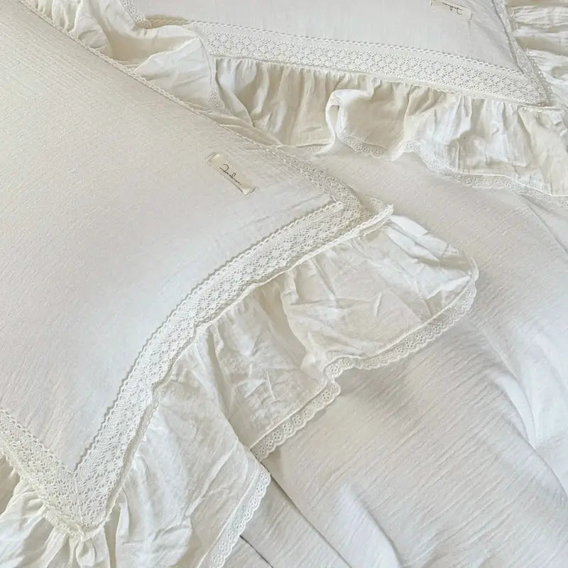 White pillowcases with delicate lace trim and ruffled edges in a french vintage white double layer crinkle yarn bedding set