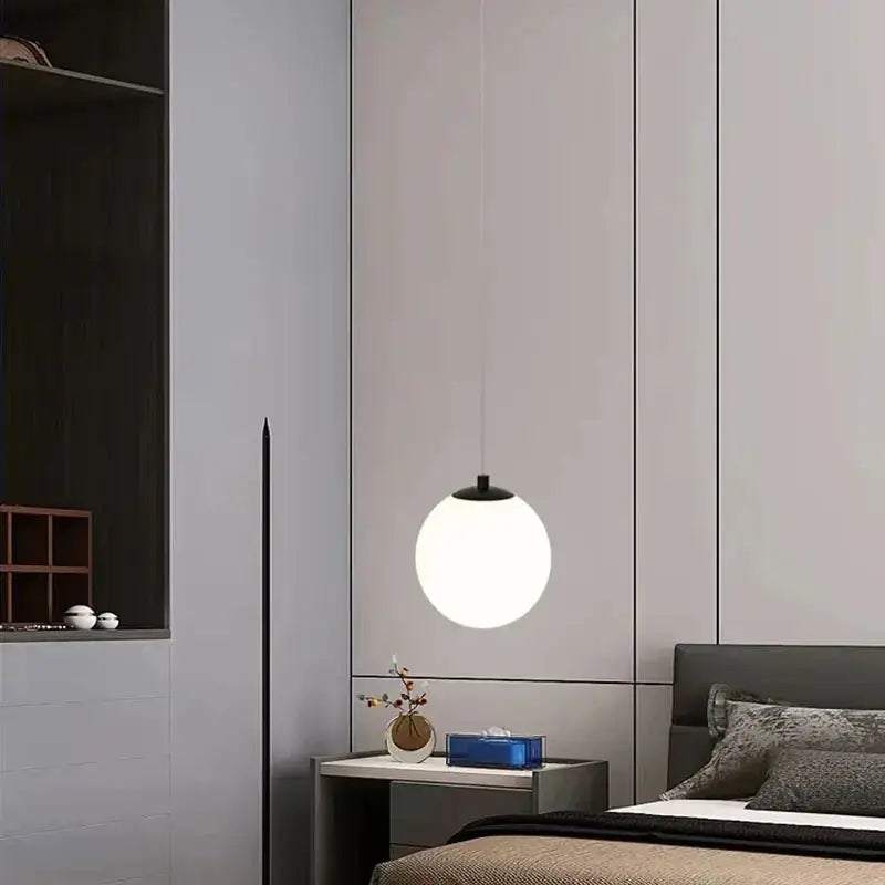 Minimalist frosted glass pendant light with a white spherical shade and black top for dining room lighting